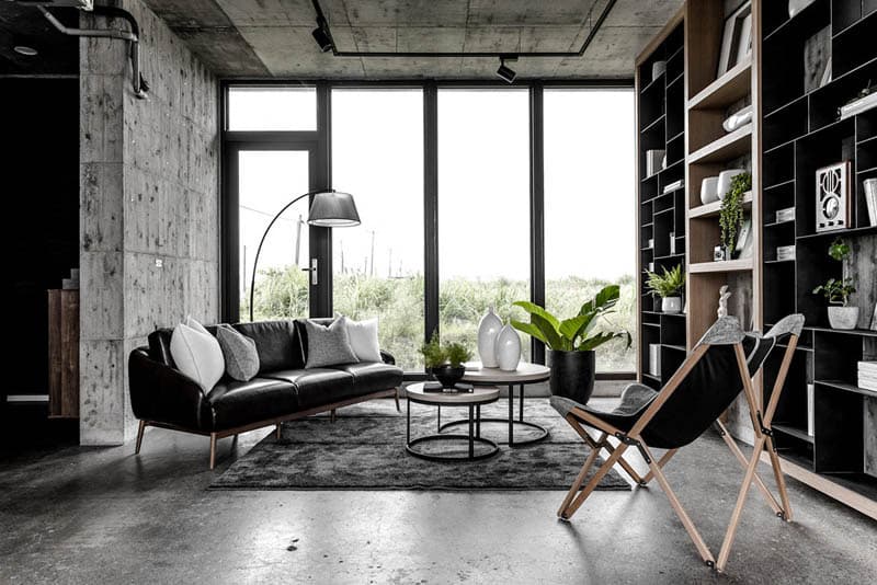 An industrial loft with concrete walls, black shelving and leather chairs
